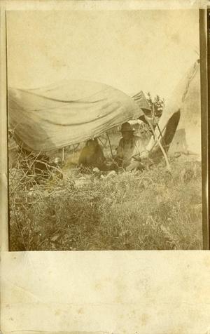 two Indians sitting under a tent in a field