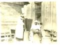 Primary view of Betty McIntosh pounding corn in mortar to make Sofke and Lydia Larney sifting pounded corn