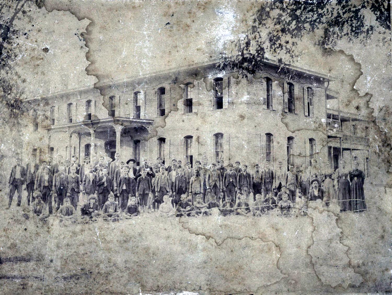 A large group of boys and teachers in front of a two story brick building.
                                                
                                                    [Sequence #]: 1 of 1
                                                