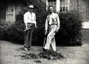 Clarence Harris and another man are seen digging a hole near a building.