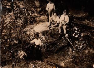 Four People Posing at Large Rock and Small Pond