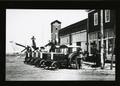 Photograph: Five Old Tractors in Front of Building