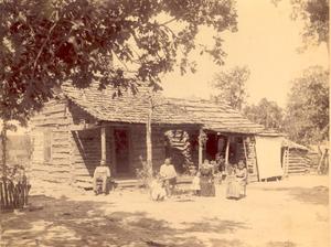 Log cabin with unknown people sitting out front.